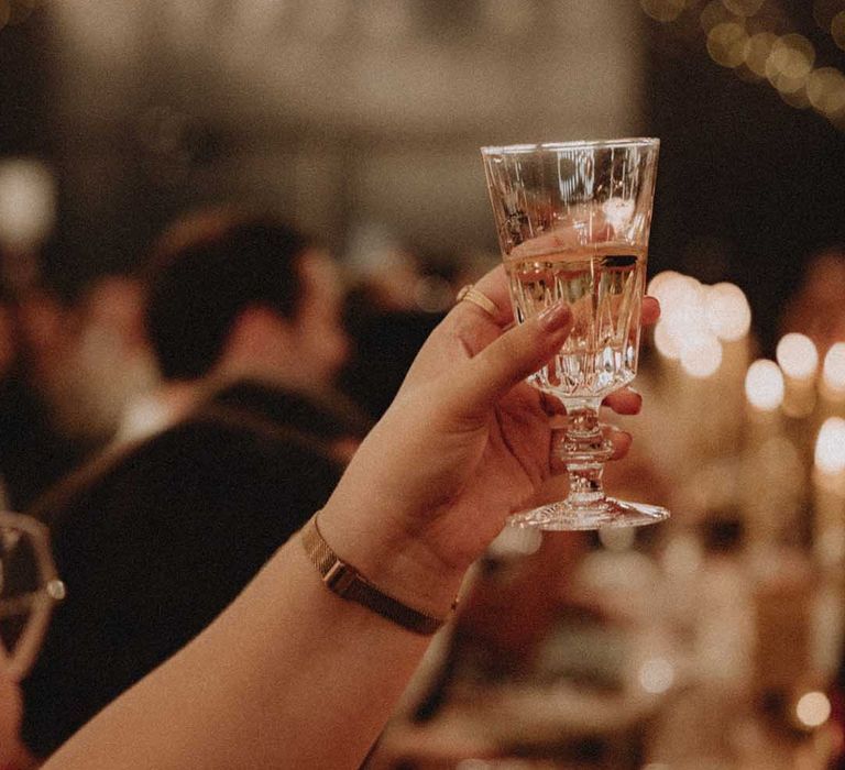 Wedding guest lifts glass during reception 