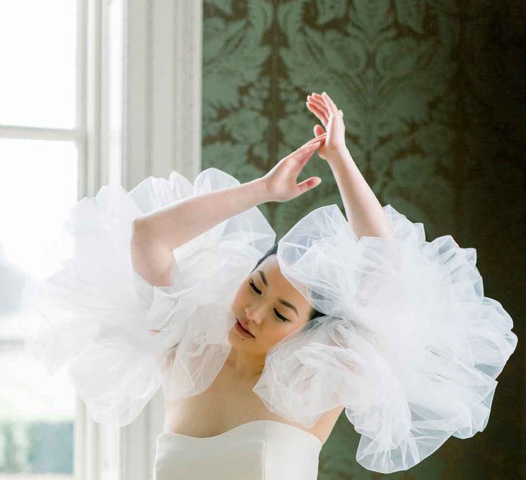 Bride posing in strapless wedding dress with puff tulle sleeves