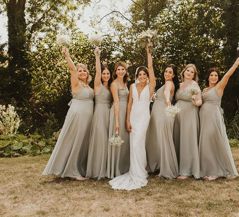 Bridesmaids in satin green bridesmaid dresses with white flower bouquet with the bride in a beaded wedding dress 