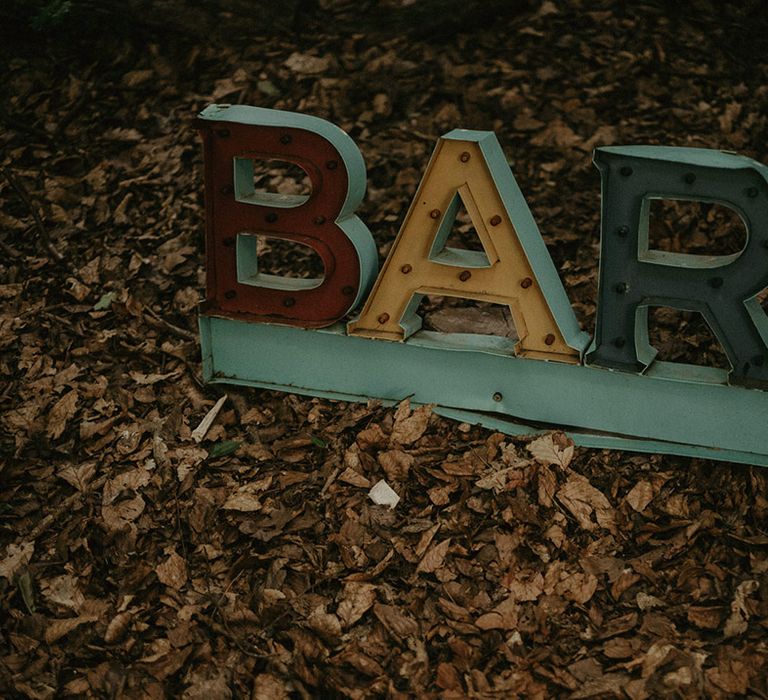 Colourful industrial style metal bar signage at outdoor wedding 