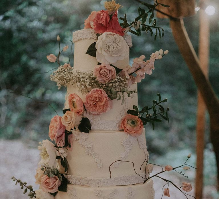 Four tier white wedding cake with pink and white flowers created with icing for outdoor woodland wedding 