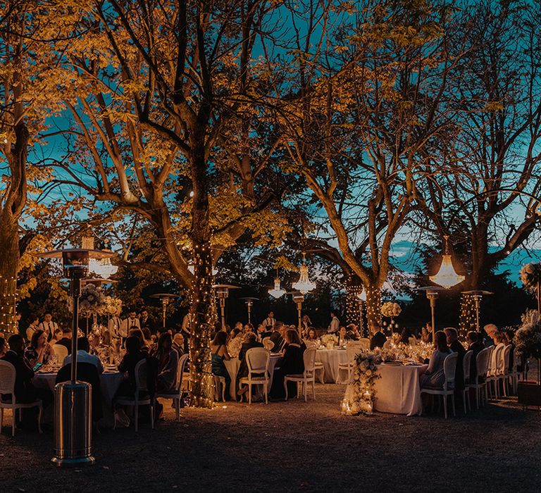 Outdoor destination wedding in Barcelona with outdoor chandeliers and fairy lights woven around the trees