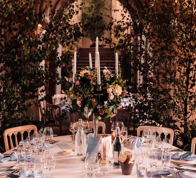 Tall wedding table centrepiece with baby blue place settings including napkins, menu, and pastel flowers and mini bread baskets 