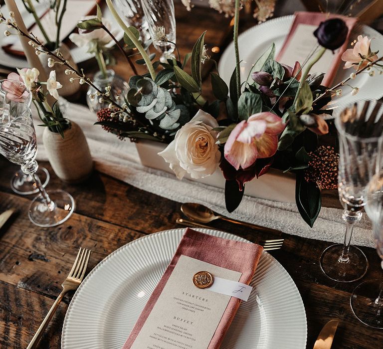 Pink wedding napkin with wedding menu resting on top with gold wax seal 