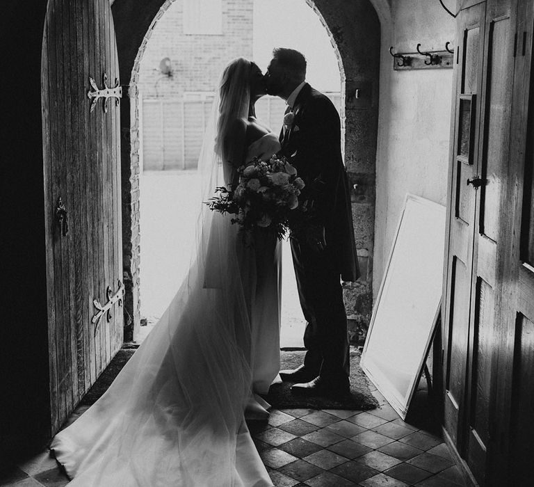 Bride in a strapless wedding dress leaning in for a kiss with the groom after their church wedding ceremony 