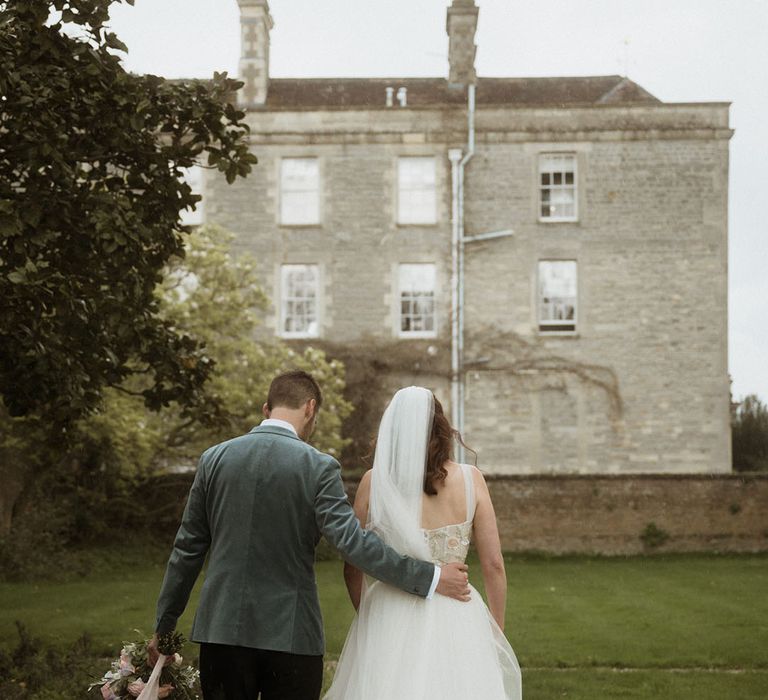 Bride in layered tulle wedding dress walking along with the groom at country house wedding 