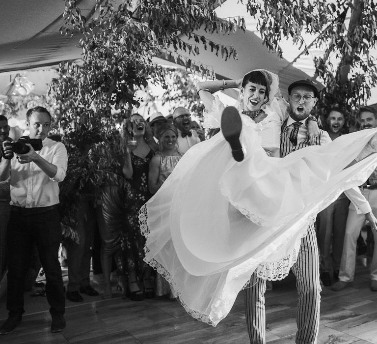 Bride in ruffle bridal separates dances with groom in pinstripe suit at tipi wedding