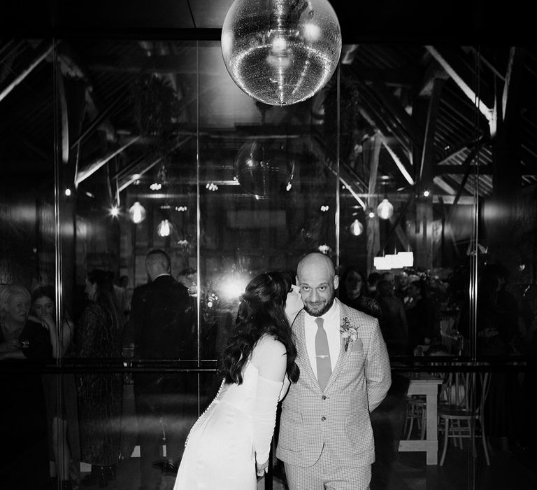 The bride and groom stand underneath disco ball