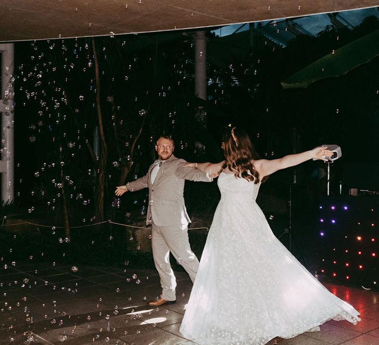 The bride and groom perform their first dance as bubbles blow across the dance floor 