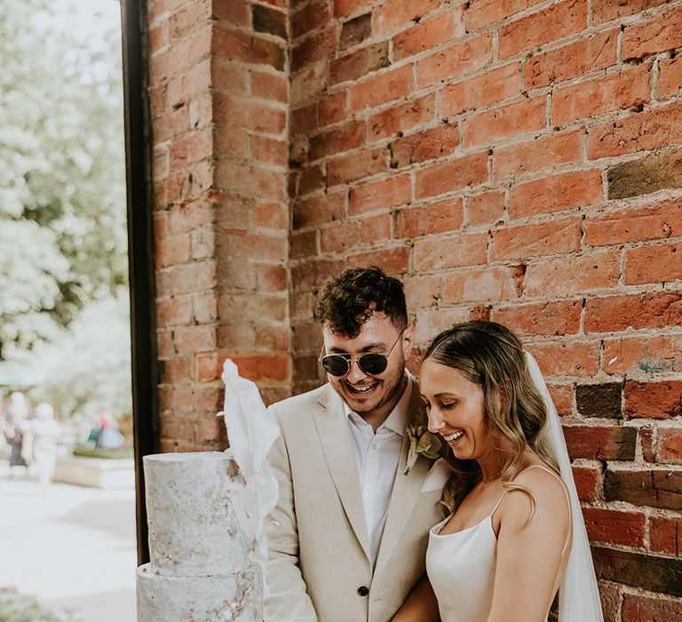 Bride and groom cut their luxury three piece wedding cake with stone effect 