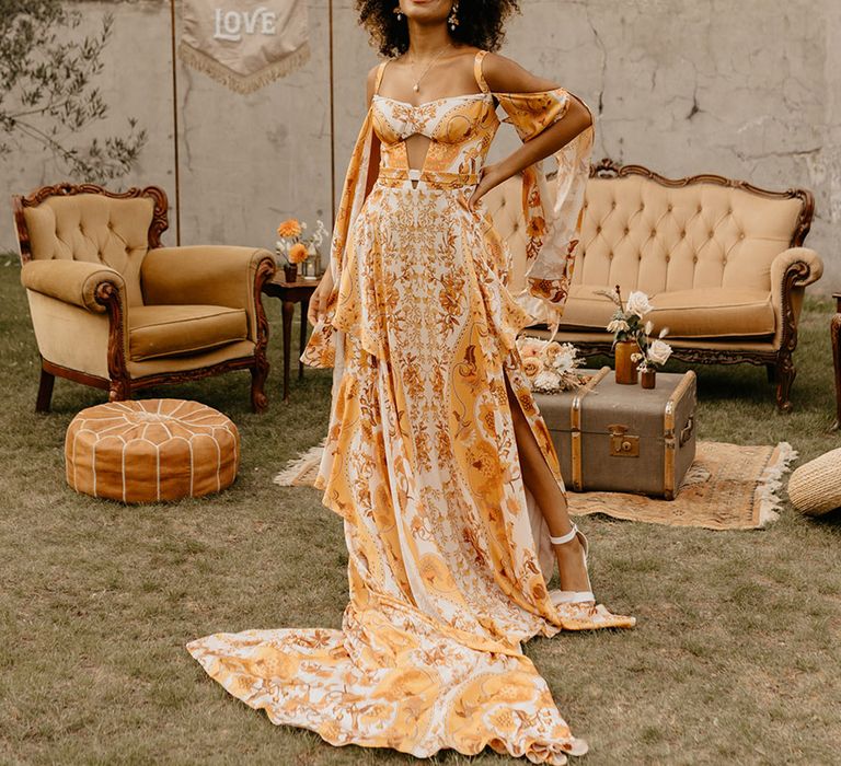 Bride in yellow and orange flower patterned wedding dress with elegant strap detailing 