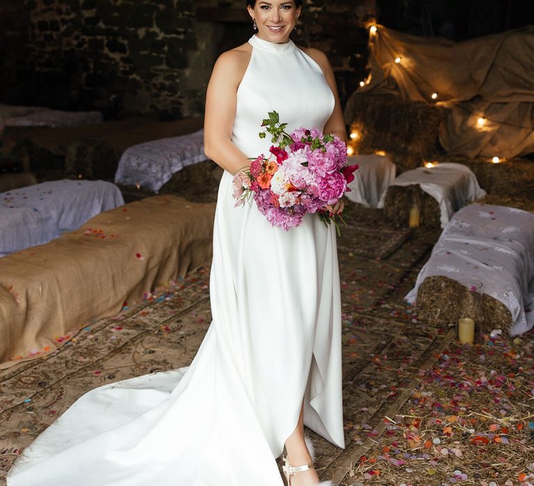 Bride in halter neck wedding dress carrying hot pink wedding bouquet