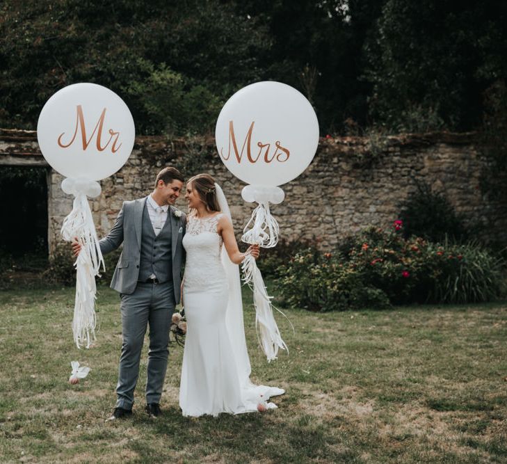 Bride and groom holding giant Mr & Mrs balloons with tassels 