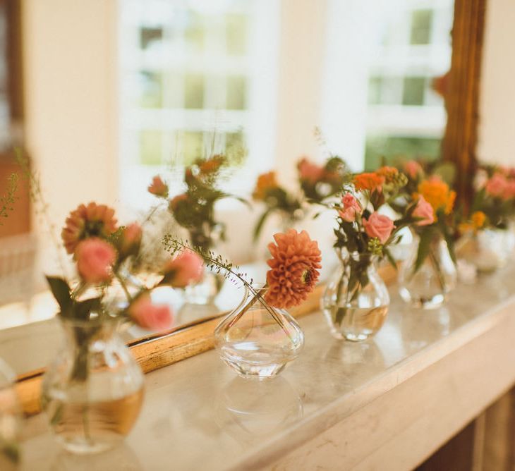 flower stems in bud vases on the fireplace 