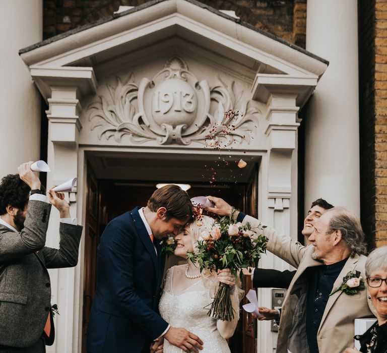 Bride & groom kiss outside registry office with confetti being thrown