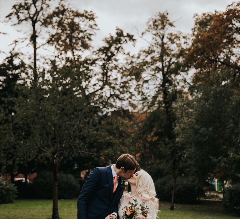 Bride & groom stand on pathway surrounded by trees 