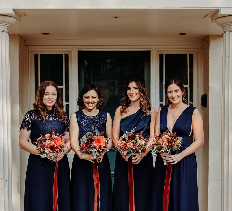 Deep blue bridesmaids dresses with contrasting Autumnal bouquet