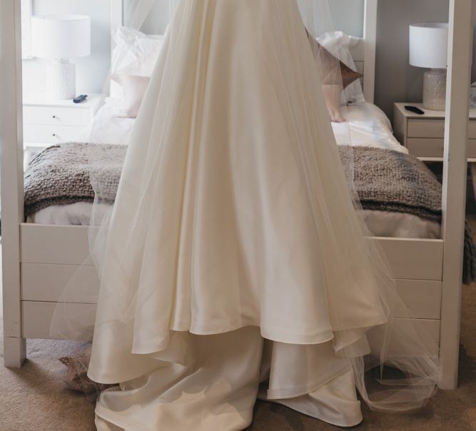 Oleg Cassini wedding dress and veil hanging up on the white four poster bed frame