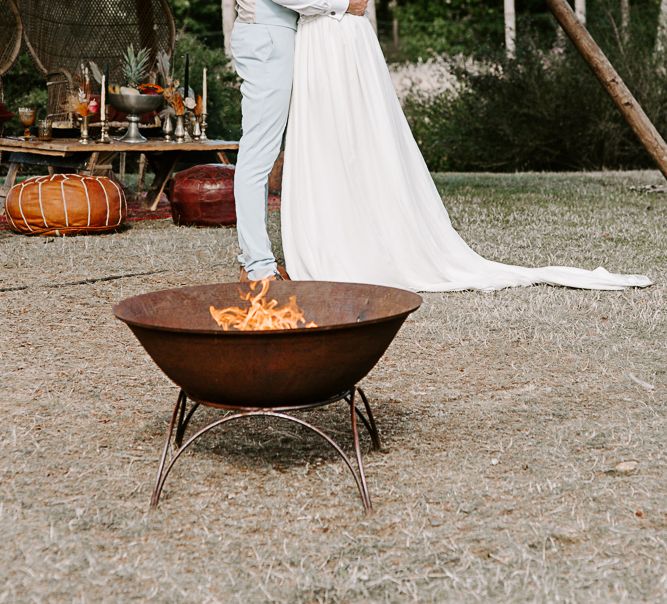 Bride & groom kiss in front of fire pit outdoors