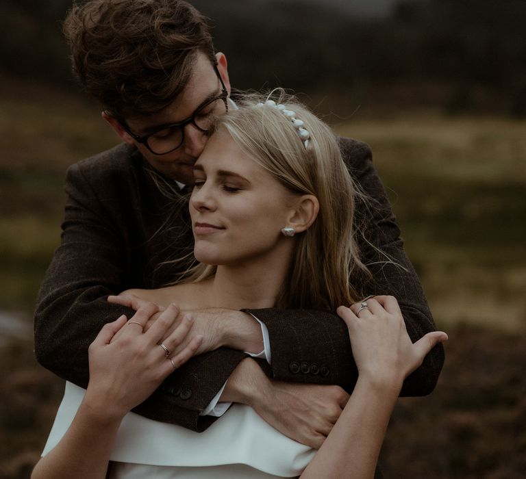 Groom embraces bride during Scottish elopement 