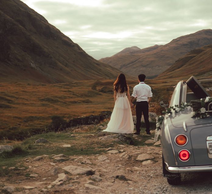 Couple walk away from vintage car in the countryside