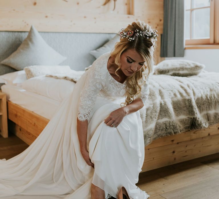 Bride with a gypsophila flower crown putting on her beige wedding shoes 