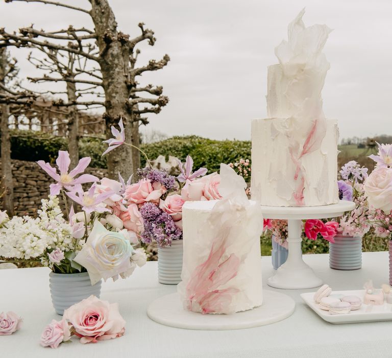 Two white wedding cakes with pastel decor and white frosting