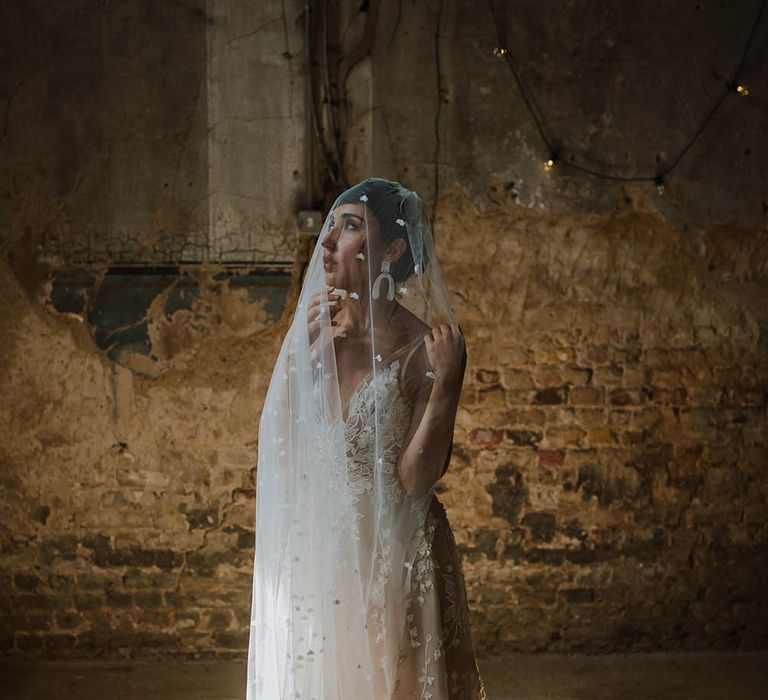 Bride in a lace wedding dress with wishbone earrings under an appliqué wedding veil 