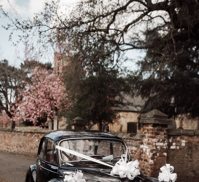 Black Morris Minor wedding car with white wedding ribbon decoration