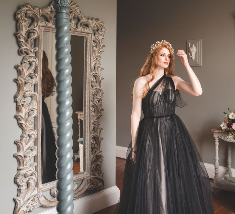 Bride on the wedding morning in a one shoulder black tulle wedding dress with long auburn hair and wire hair accessory 