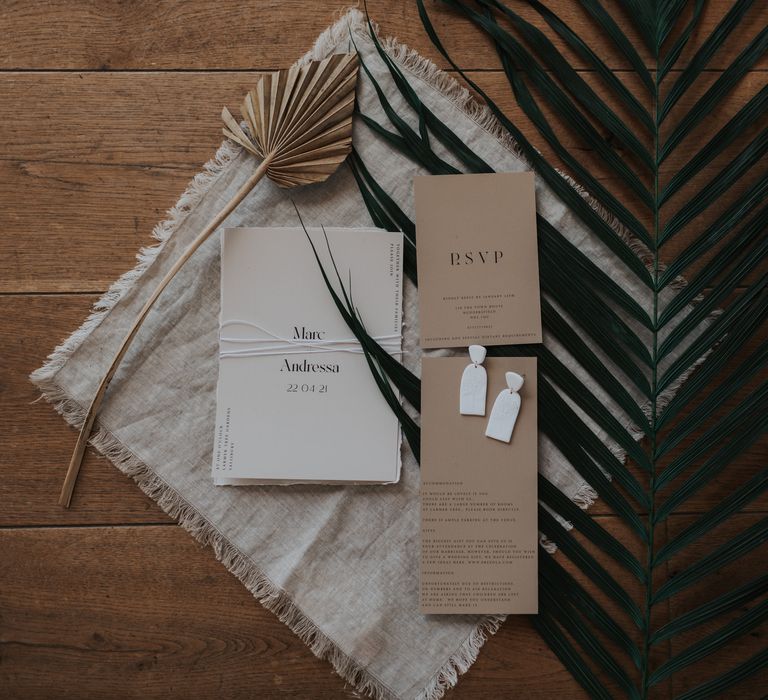 White and stone contemporary wedding stationery on a giant leaf 