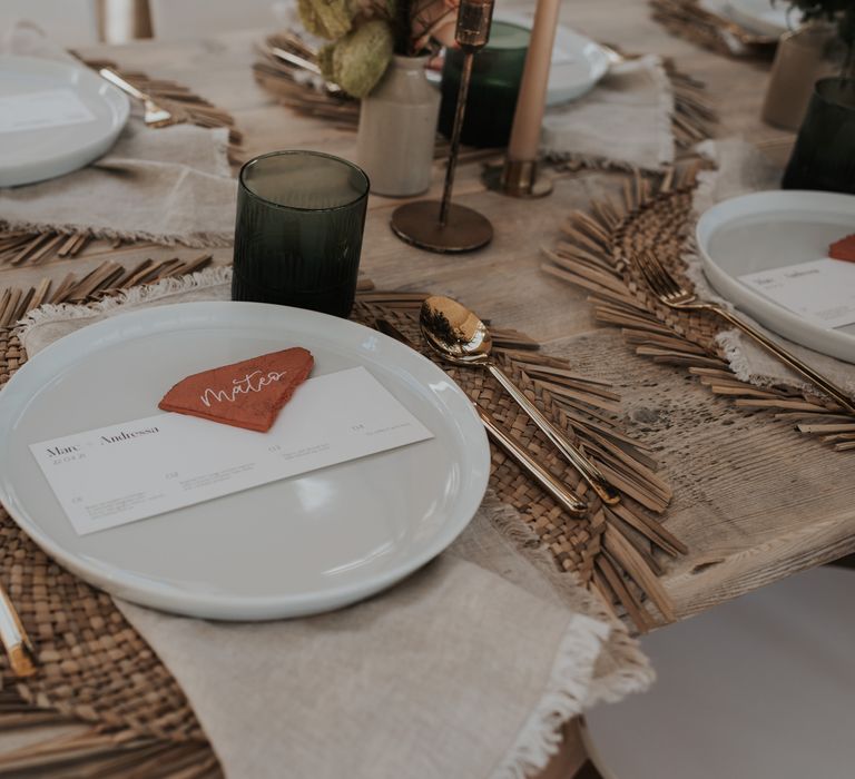 Place setting with wicker place mat, white tableware and gold cutlery 