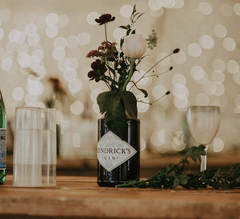 Empty Hendricks gin bottle filled with florals upon wooden table