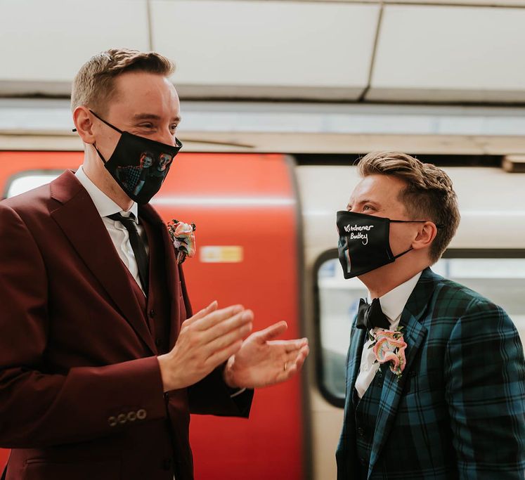 Grooms stand within tube station as they wear black face masks on their wedding day | Kim Williams Weddings