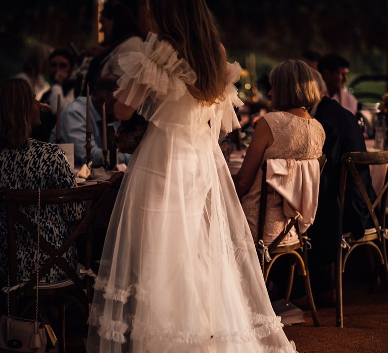 Bride in white Halfpenny London Mayfair dress stands in marquee during garden wedding reception in Cornwall