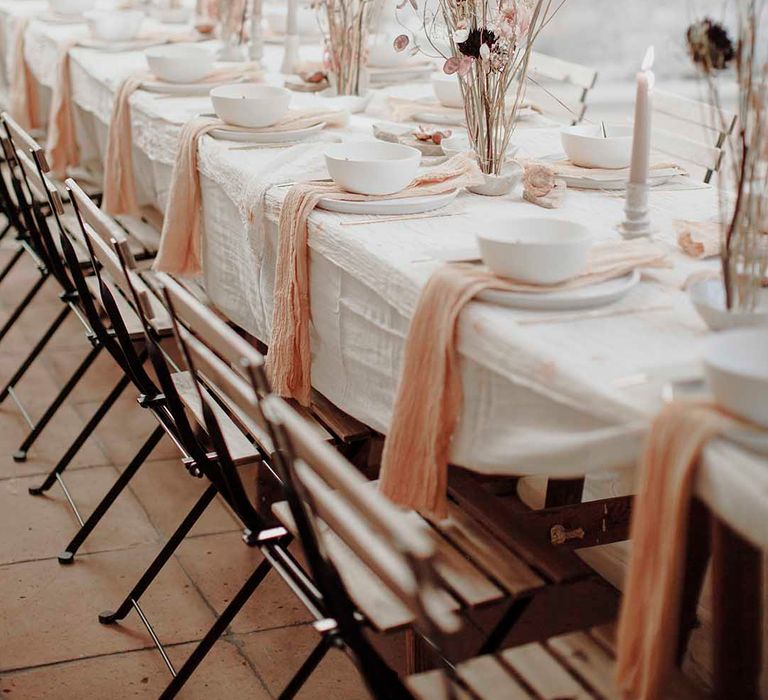 Modern gothic wedding table decor with long elegant flower stems ascending from rustic cream glazed finger bowls