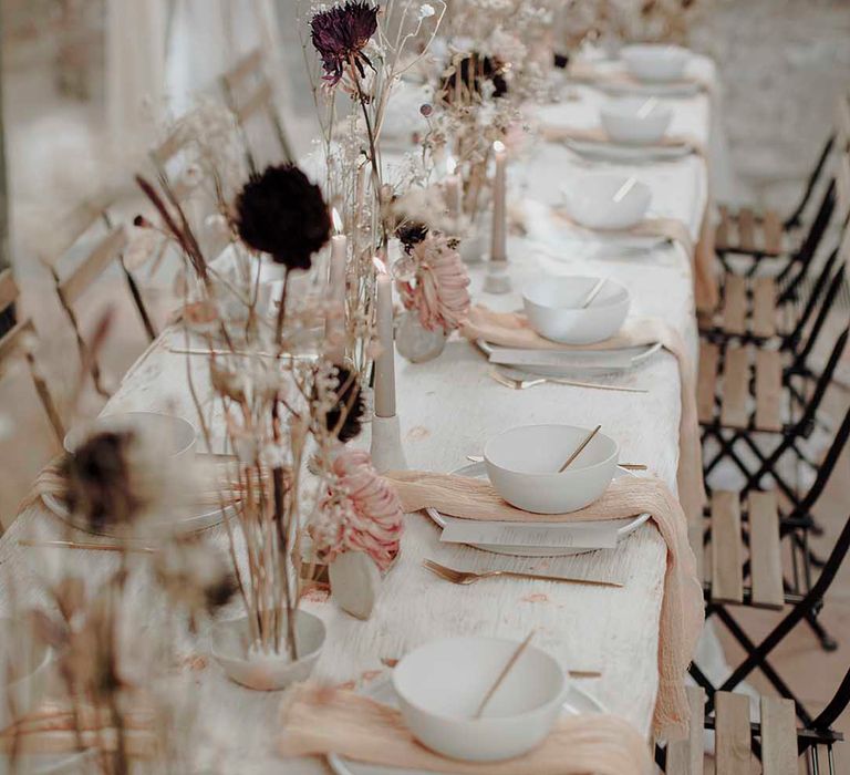 Minimalist wedding table decor with dried flower stems in ceramic vases, candles and natural linens 