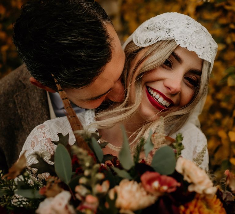 Groom kissing his brides neck with bright red lipstick and lace Juliet cap veil 