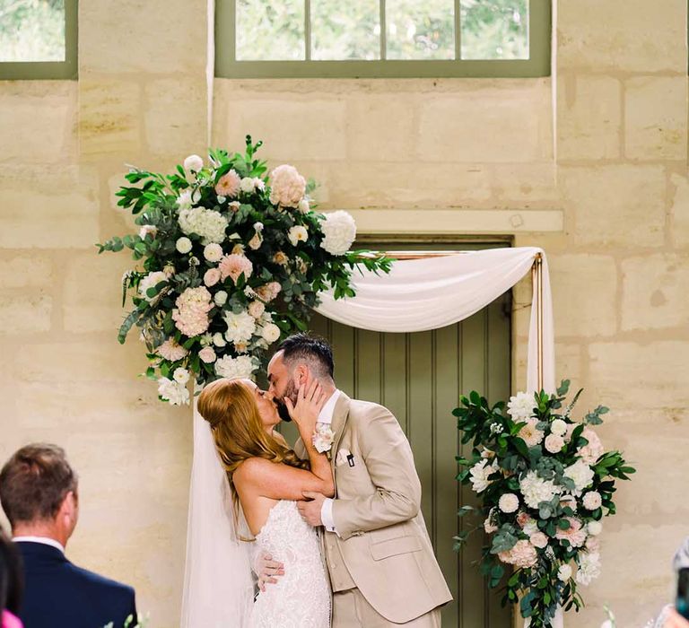 Groom holds back his bride whilst kissing her during ceremony