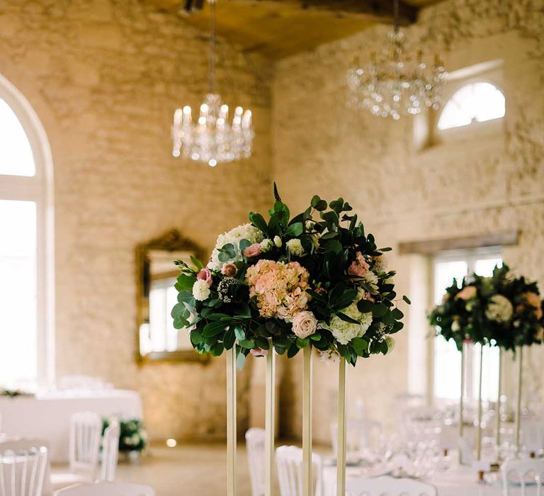 Rustic wedding venue complete with white tablecloths and large floral bouquet centrepiece 