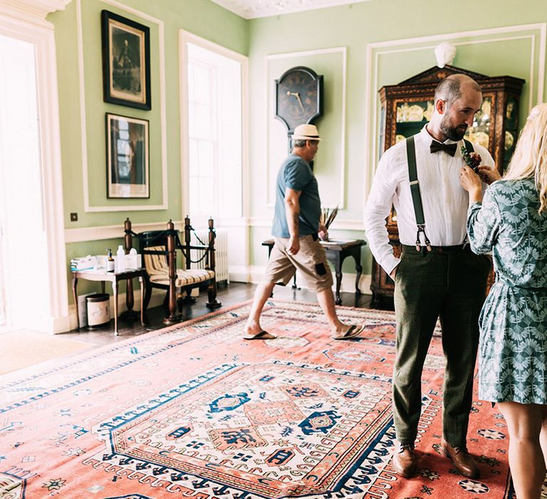 Groom gets his buttonhole fixed in stunning green room