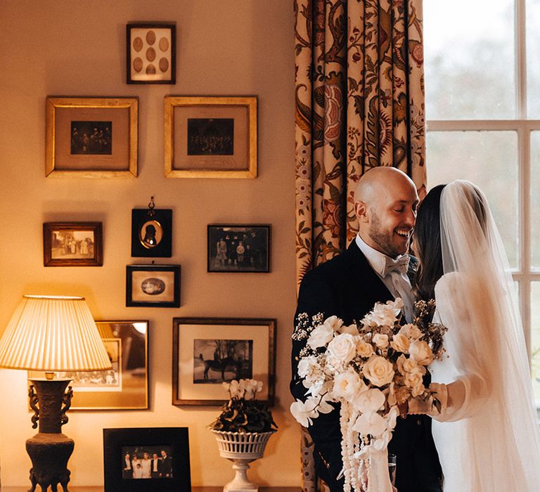 Bride in a long cathedral length veil holding an all-white rose winter wedding bouquet 