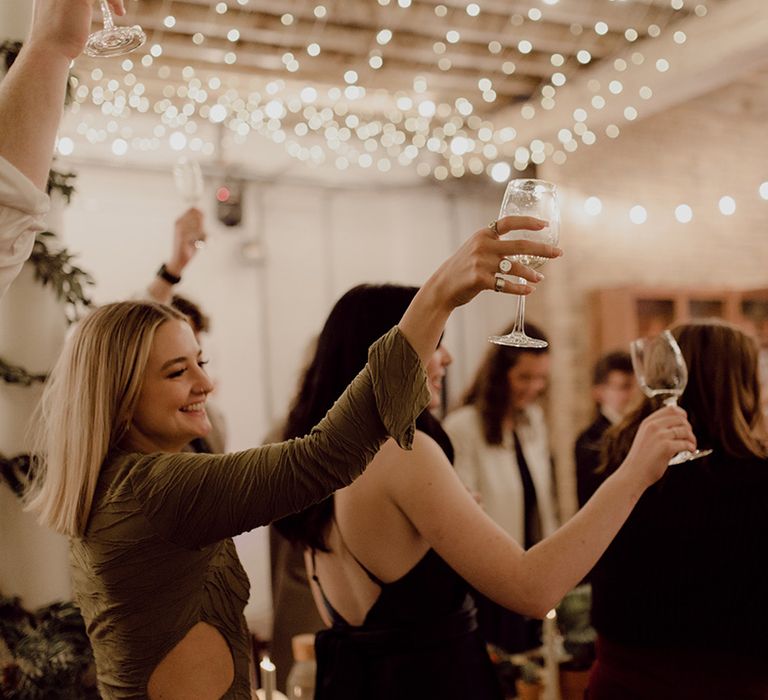 Wedding guests raise a toast to the bride and groom at fairy lit city wedding venue