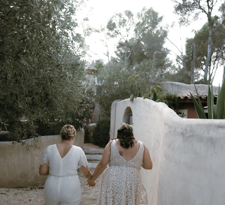 Brides walk together holding hands around their outdoor destination wedding venue in Barcelona, Spain 