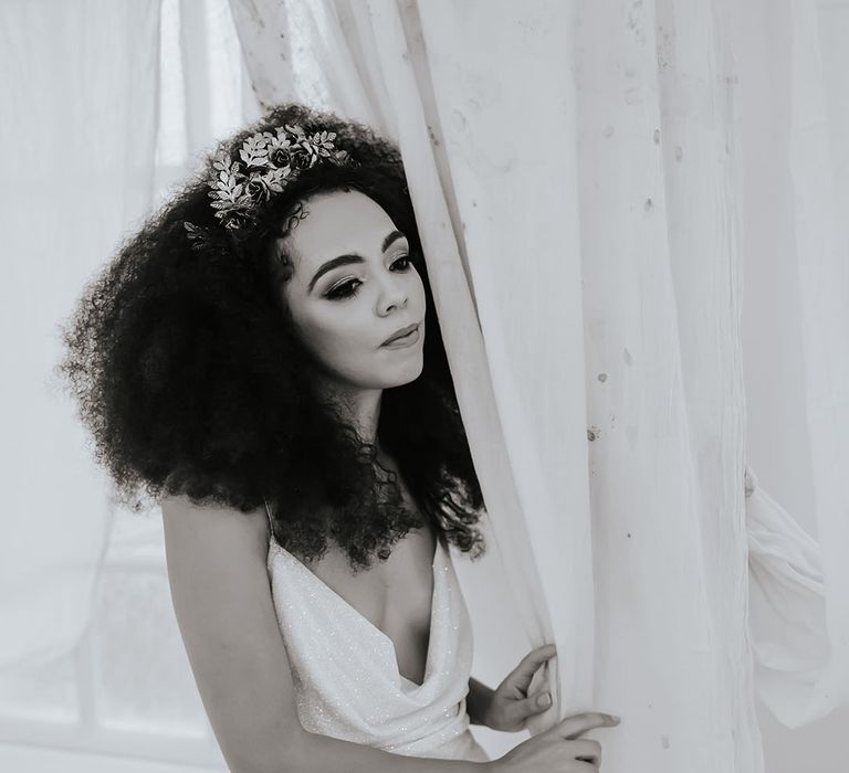 Black bride in a sparkly wedding dress with cowl front with naturally curly afro hair and hair accessory