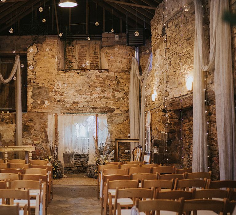 Wedding venue ceremony room with drapery, fairy lights and boho macrame decor