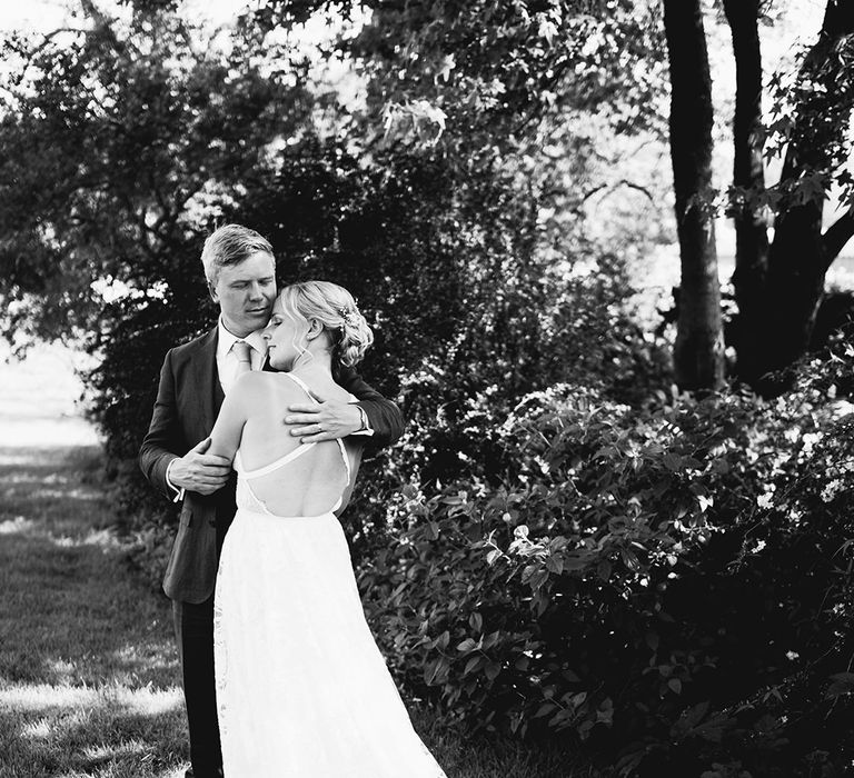 Bride rests her head on the groom's chest as he holds her after home wedding ceremony