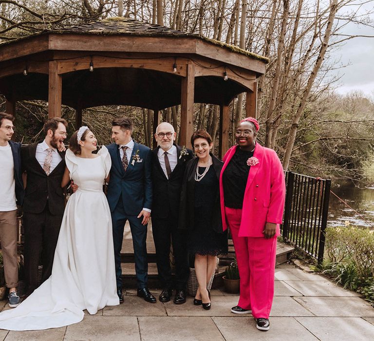 Bride and groom and wedding guests pose together as they stand outside Bowers Mill wedding venue