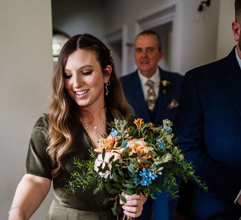 Bridesmaid in olive green dress and dainty matching earrings and necklace picks up some confetti 