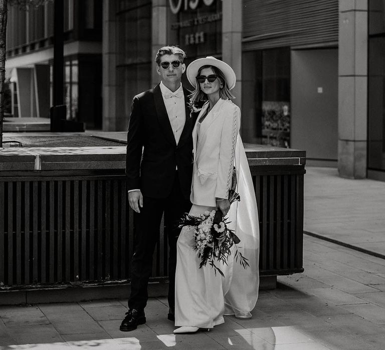 Bride and groom pose together wearing their sunglasses and suits for town hall wedding